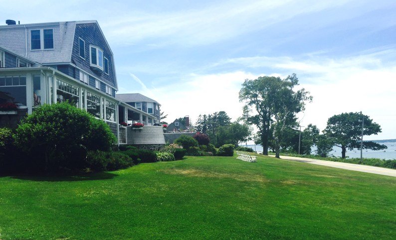 The gracious dining porch overlooks gardens and the ocean beyond